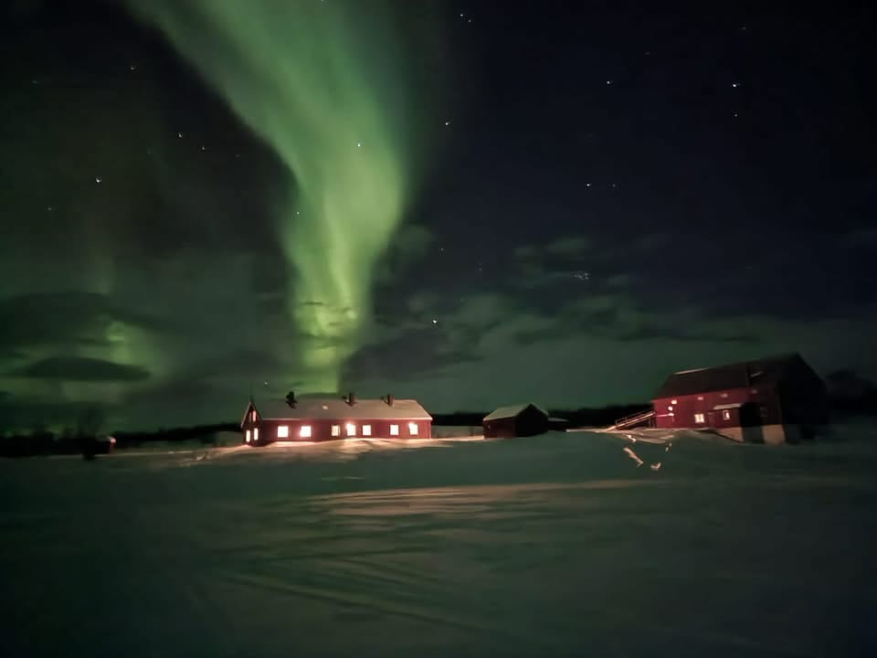 Nordlys over hytta og snøen